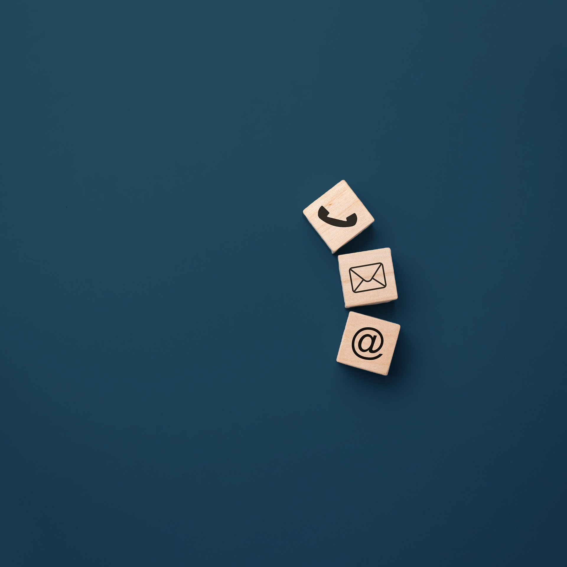 Drei Holzwürfel mit Icons, die unterschiedliche Kontaktmöglichkeiten symbolisieren.